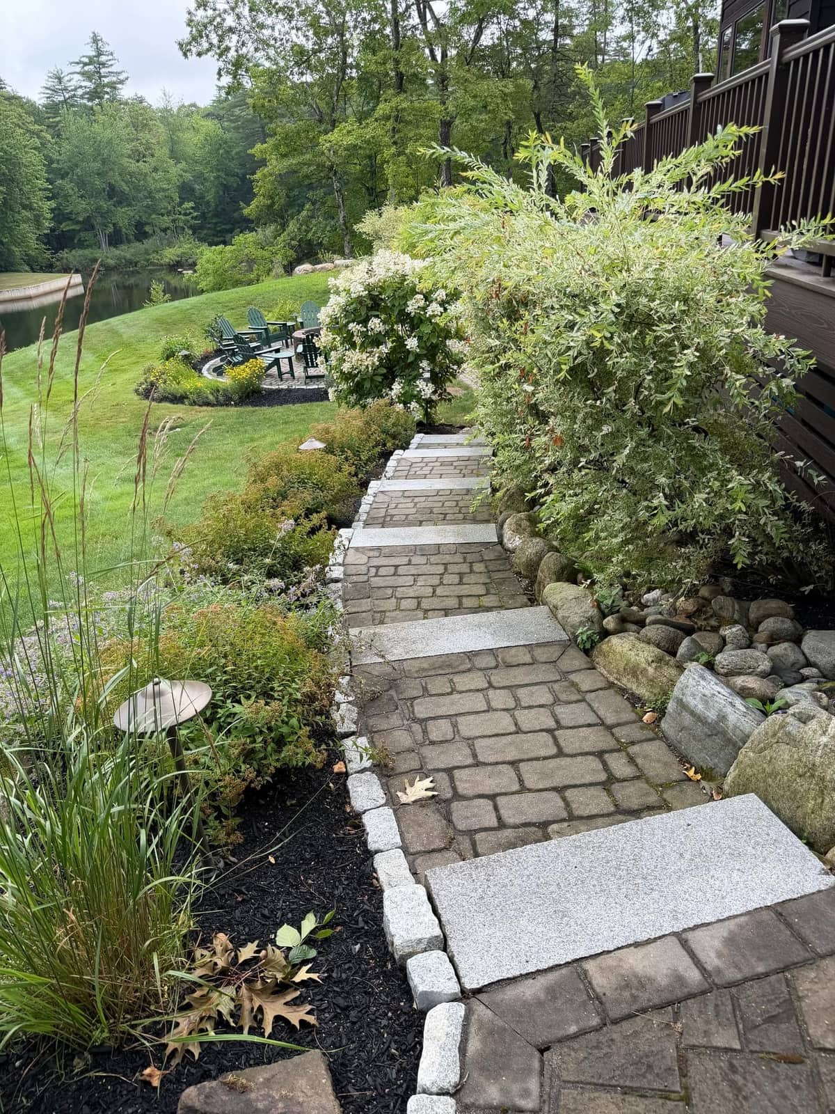 Cobblestone path with granite plank steps beside boulder retaining wall