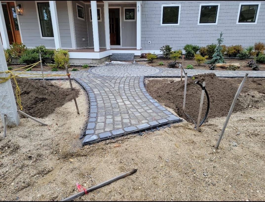 Cobblestone entry walkway with circular medallion in front of a new shingled home