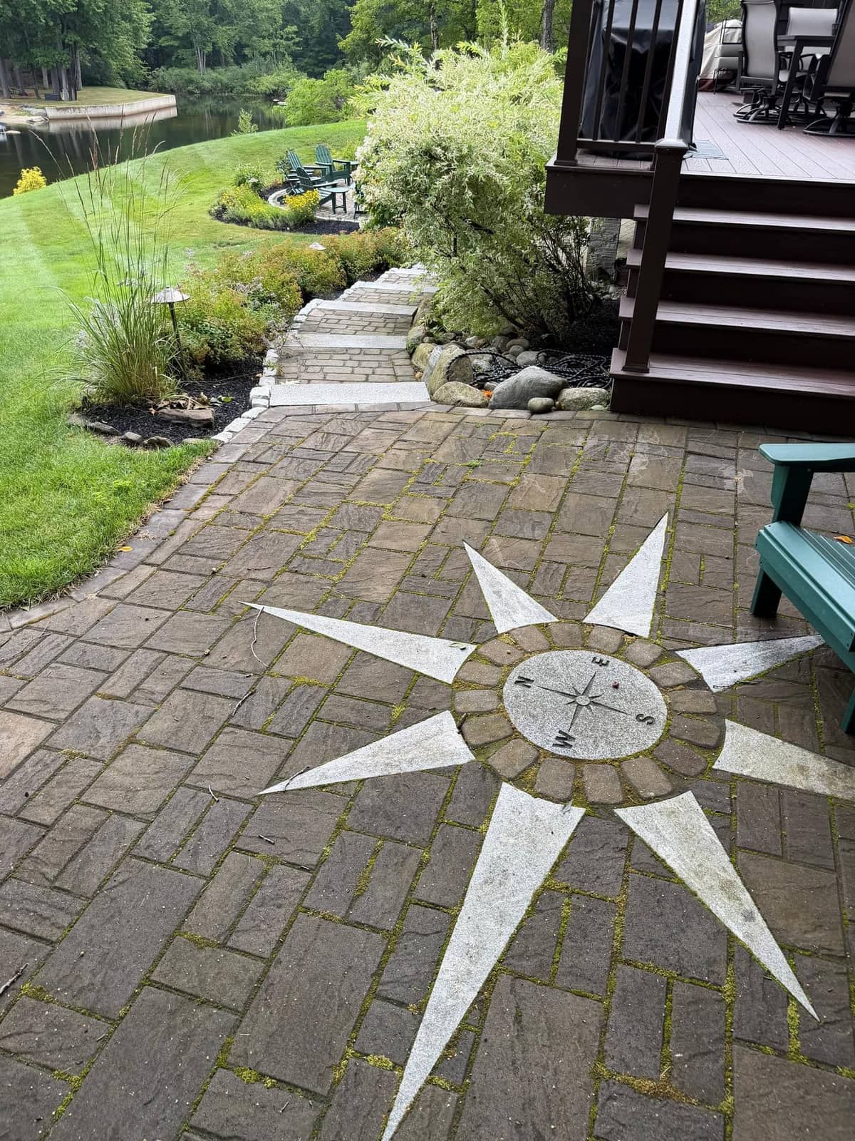 Paver patio with an inlaid granite compass rose medallion beside a lakeside home