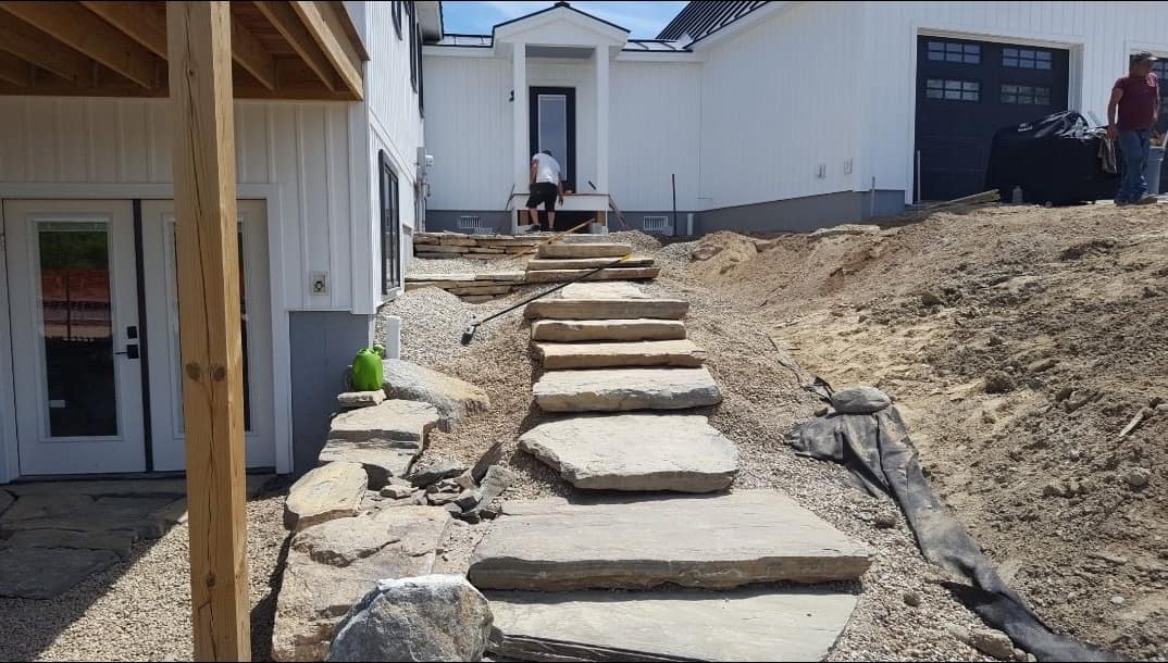 Natural stone slab steps climbing to a white modern farmhouse