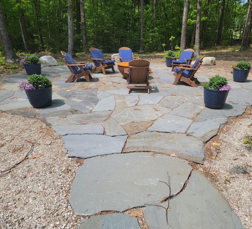 Natural flagstone fire pit patio with Adirondack chairs in a pine clearing