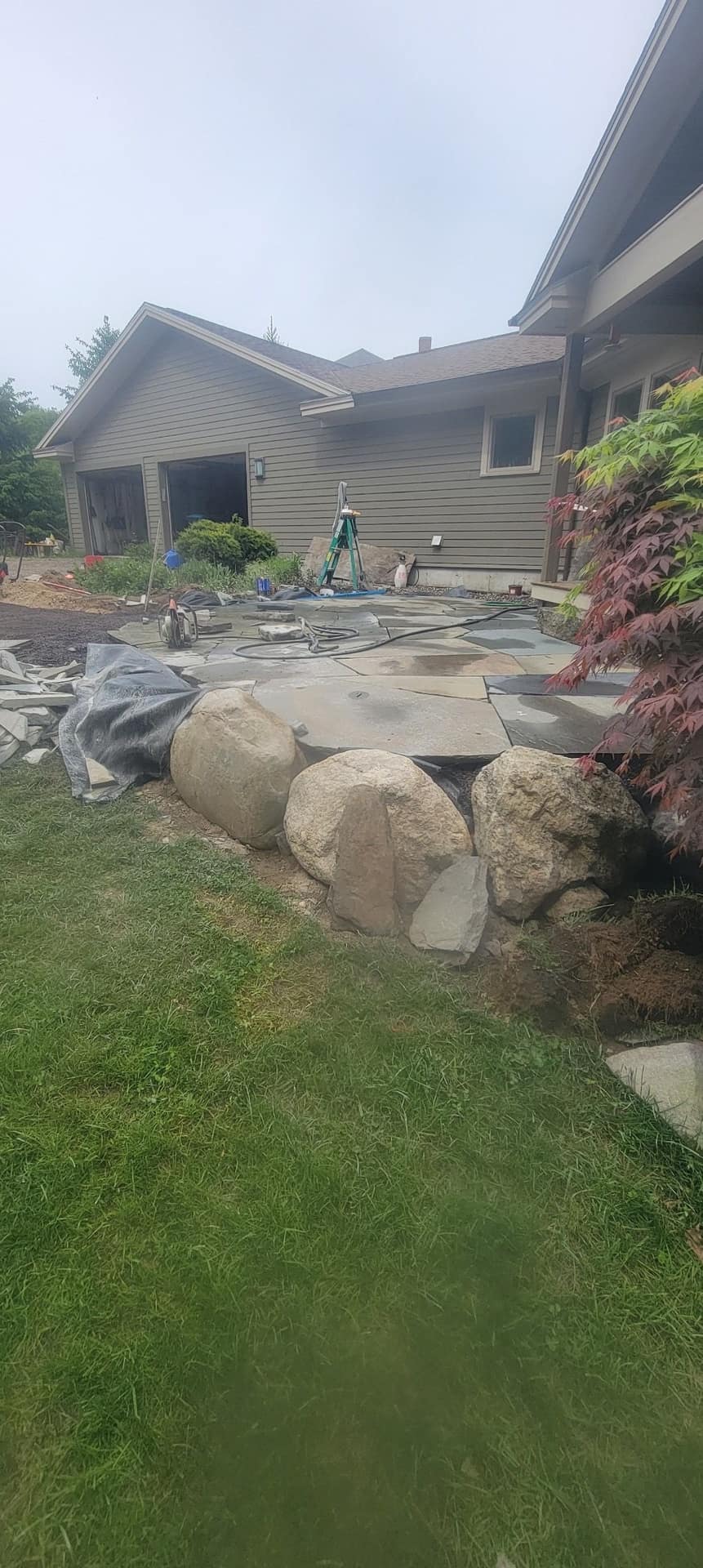 Flagstone patio under construction with rounded boulder edging