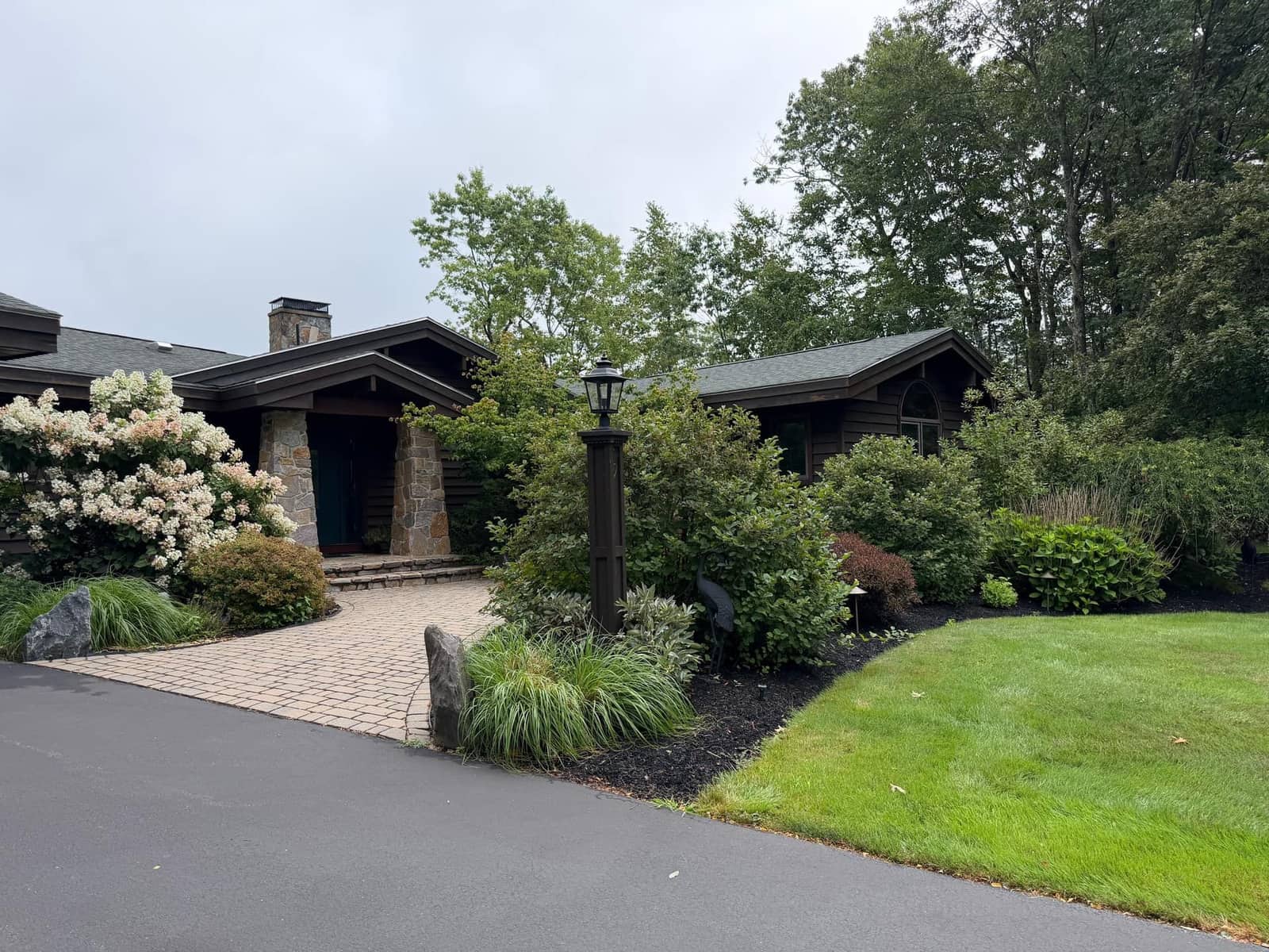 Craftsman home entry with paver walkway framed by layered foundation plantings in Cumberland, Maine