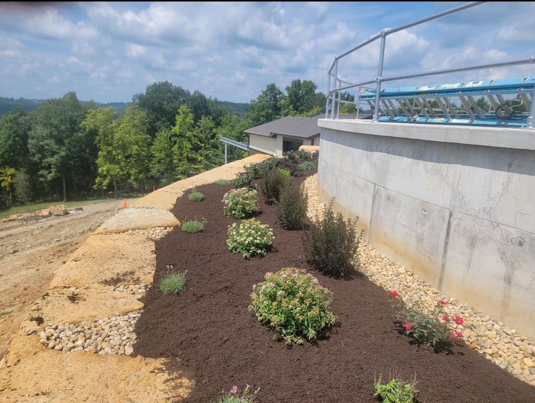 Curved hillside planting bed with stone accents and fresh mulch