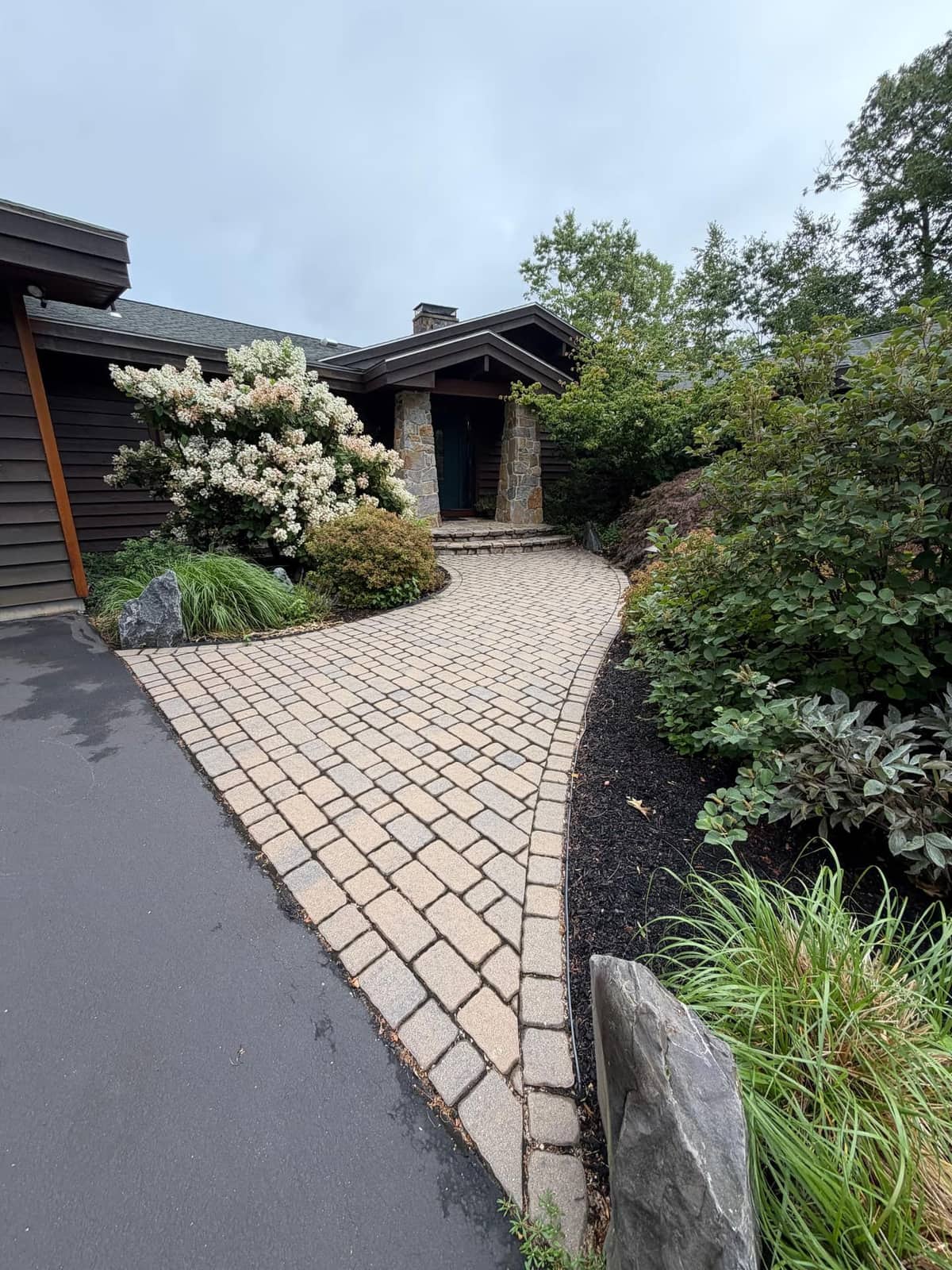 Wide paver walkway flaring to a stone-pillared entry