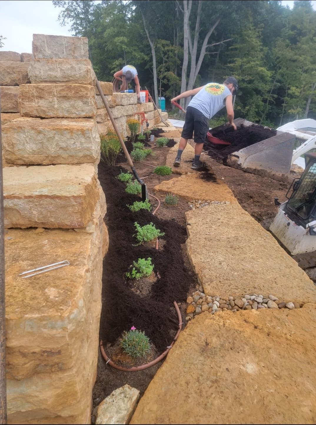 Crew planting perennials along a stacked stone block wall