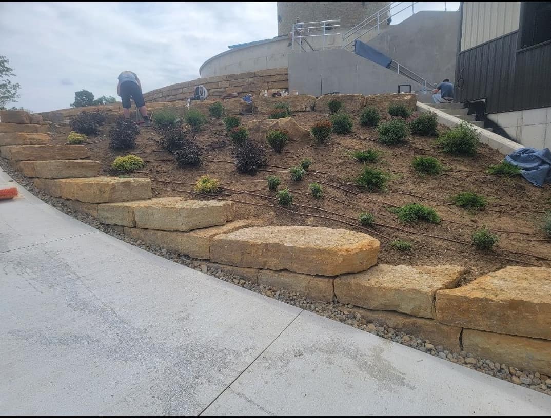 Terraced natural stone retaining walls with new hillside plantings